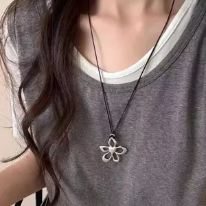 Dettaglio di un ciondolo a fiore in argento con petali traforati e cuore su cordino nero