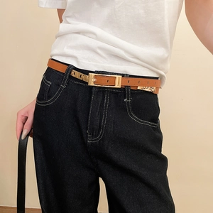Close-up of vintage brown leather belt with gold metal buckle on a white t-shirt and jeans