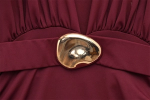 Close-up of wine red V-neck dress with elegant gold organic pebble metal buckle on the waist