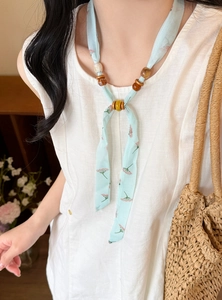 Detail of light blue floral print chiffon necklace with decorative wooden beads
