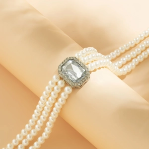 Close-up of triple-row pearl necklace with emerald-cut crystal centerpiece and silver accents
