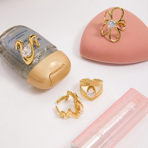Detail of four gold zircon rings set including floral hollow and wave designs on white background