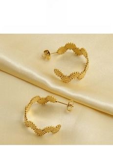 Détail de boucles d'oreilles créoles en acier plaqué or 18 carats avec texture plissée