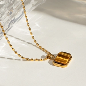 Macro detail of 18k gold stainless steel necklace with rectangular tiger eye stone