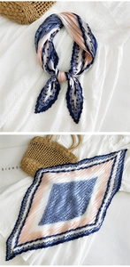 Dettaglio di foulard in seta a pieghe con motivo geometrico blu e rosa su borsa di paglia