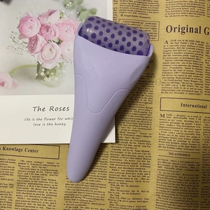 Detailed view of a purple ice face roller with textured head on a floral background