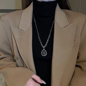 Vue macro du pendentif goutte en pierre noire et halo de diamants sur collier long en V