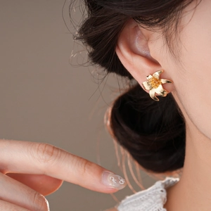 Macro view of gold flower stud earring showing intricate petal texture and details