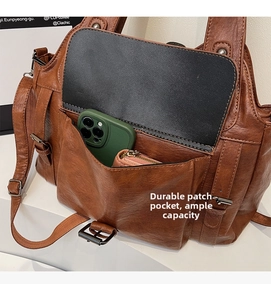Detail view showing large front pocket of a vintage brown tote bag with phone and wallet