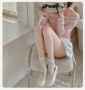 Detail of cream Mary Jane shoes with cross straps and bow-decorated ruffle socks