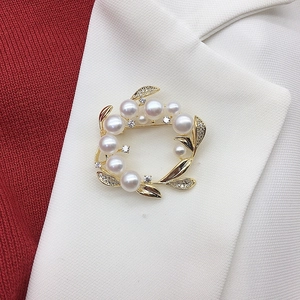 Detailed close-up of a gold floral wreath brooch with natural freshwater pearls and crystals