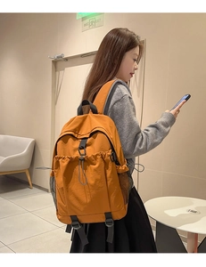 Seitenansicht eines großen orangefarbenen Segeltuchrucksacks, getragen von einem Modell