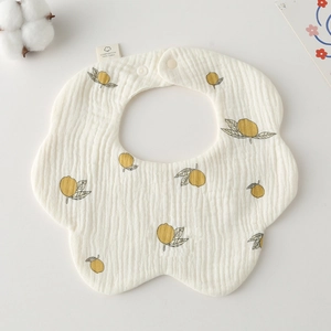 Detail of petal-shaped cotton bib featuring lemon print and adjustable snap closure