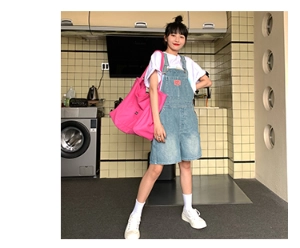 Detail of blue denim overall shorts paired with a white T-shirt in a retro kitchen setting