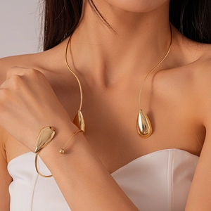 Détail d'un collier torque et bracelet manchette dorés à goutte d'eau sur un mannequin