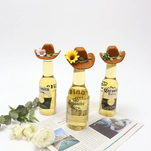 Detailed view of three brown mini cowboy hats with floral accents on glass bottles