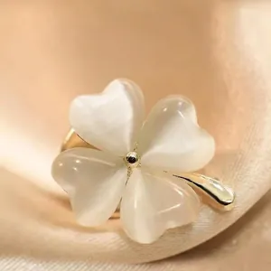 Elegant gold four-leaf clover brooch with opal stones on beige silk fabric