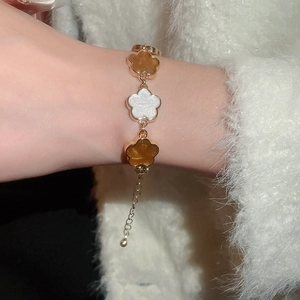 Gros plan détaillé d'un bracelet fleuri vintage doré aux pétales blancs et ambrés