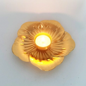 Golden lotus-shaped metal candle holder with a burning tea light on white background