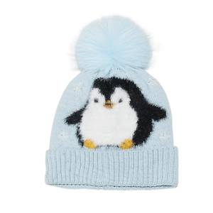 Macro detail of a light blue winter knit hat featuring a cute penguin and fluffy pom-pom