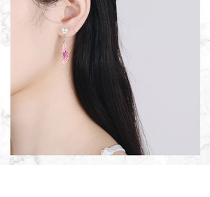 Detail view of pearl earrings with purple gradient wings worn on earlobe