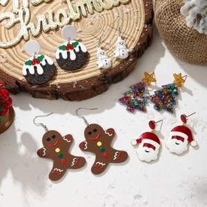 Flat lay of colorful Christmas earrings featuring Santa, snowman, and tree designs