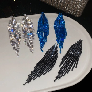 Détail de trois paires de boucles d'oreilles à pompons en bleu, argent et noir