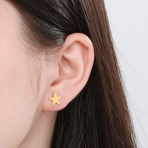 Gros plan d'une boucle d'oreille étoile dorée portée sur l'oreille avec fini métallique