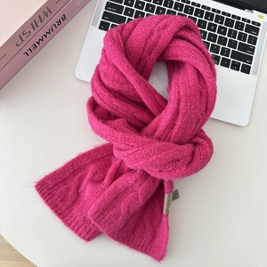Detail view of pink cable knit wool scarf with soft texture on a minimalist desk setup