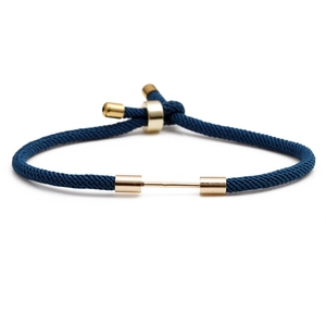Adjustable navy blue woven rope bracelet with gold metal clasp on white background