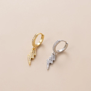Detail view of gold and silver hoop earrings with lightning pendants and cubic zirconia