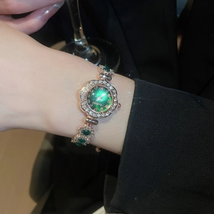 Close-up of rose gold watch bracelet with green dial and rhinestones on a wrist