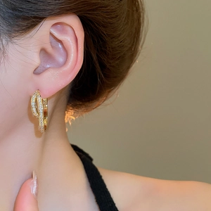 Detail of 18k gold plated U-shaped earrings with paved zircons worn by a model