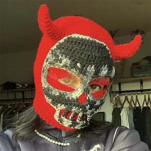 Macro detail of red handmade crochet balaclava with skeleton face and devil horns