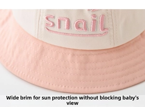 Detail of the snail letter embroidery on the pink and beige cotton sun hat for babies