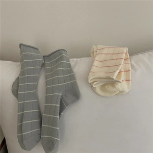 Close-up of Morandi color striped cotton socks in grey and beige on a soft fabric surface
