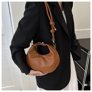 Detail of a brown crescent shoulder bag with knotted strap and smooth faux leather texture