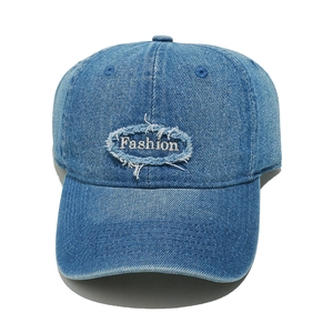 Detailed macro view of distressed denim fabric with embroidered Fashion patch on baseball cap