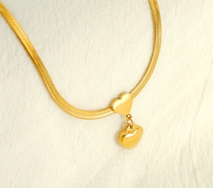 Macro shot of gold-plated stainless steel snake chain with layered double heart pendants