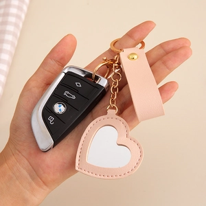 Pink heart mirror keychain with leather strap held in hand for size perspective