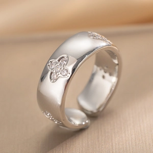 Polished silver four-leaf clover ring with sparkling zircon stones on silk background