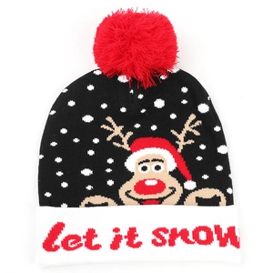 Detail of knit hat with reindeer pattern, red pom-pom and Let it snow embroidery