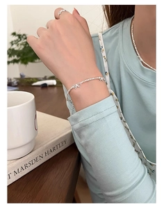 Dettaglio di bracciale e anello in argento con fiocco su modella in stile cozy