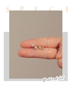 Macro shot of star shaped S925 silver stud earrings with zircons in silver and gold colors