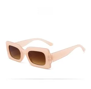 Detail view of retro pink rectangular thick frame sunglasses with brown gradient lenses