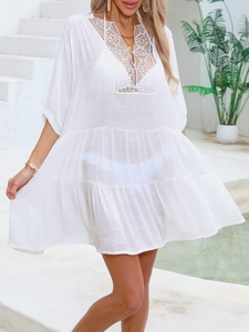 Detail of white sheer beach cover-up featuring intricate crochet lace neckline and tiered skirt
