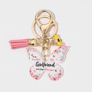 Detail of butterfly acrylic keychain with pink tassel, bee charm and floral text print
