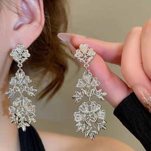 Close-up of triple-layered floral hollow pendant earrings with vintage silver finish