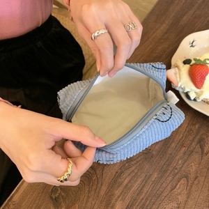 Detail showing the inner space of a blue corduroy makeup bag with smiley embroidery