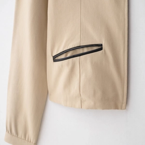 Giacca beige con zip, bordi neri a contrasto e tessuto testurizzato con taglio aderente